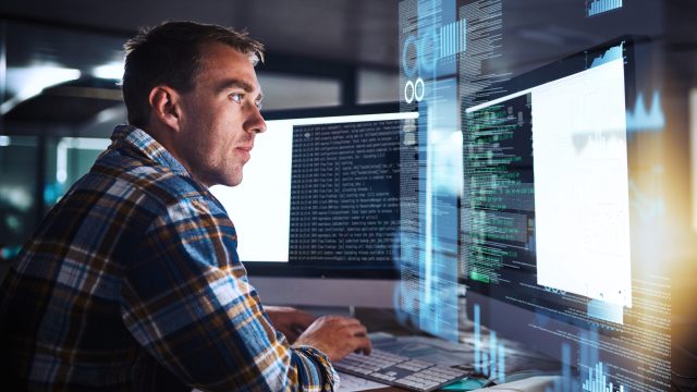 Shot of a young programmer working at his computer with an overlay of computer graphics